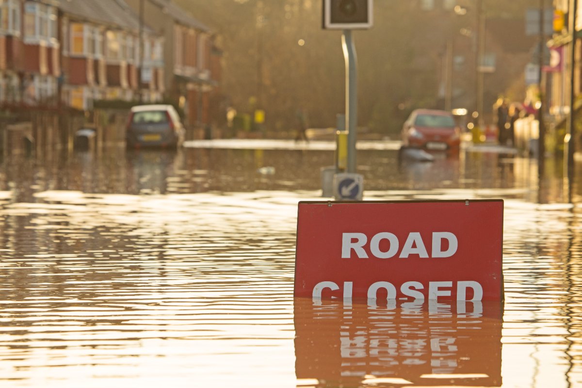 A 'road closed' sign partly covered in floodwater. Credit: AC Rider from Shutterstock