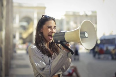 A lady shouting into a megaphone. Copyright: Andrea Piacquadio | Pexels