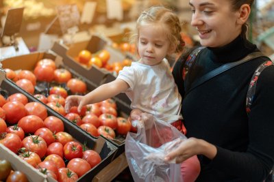 Young woman with small child buying tomatoes.. Copyright: andreonegin | shutterstock